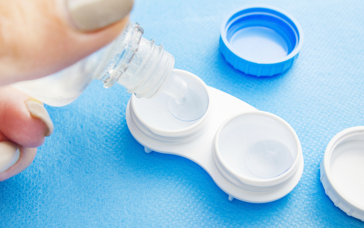 Puting contact lens solution drops into a case