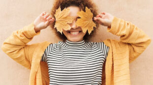 curly-young-woman-covering-her-eyes-with-leaves